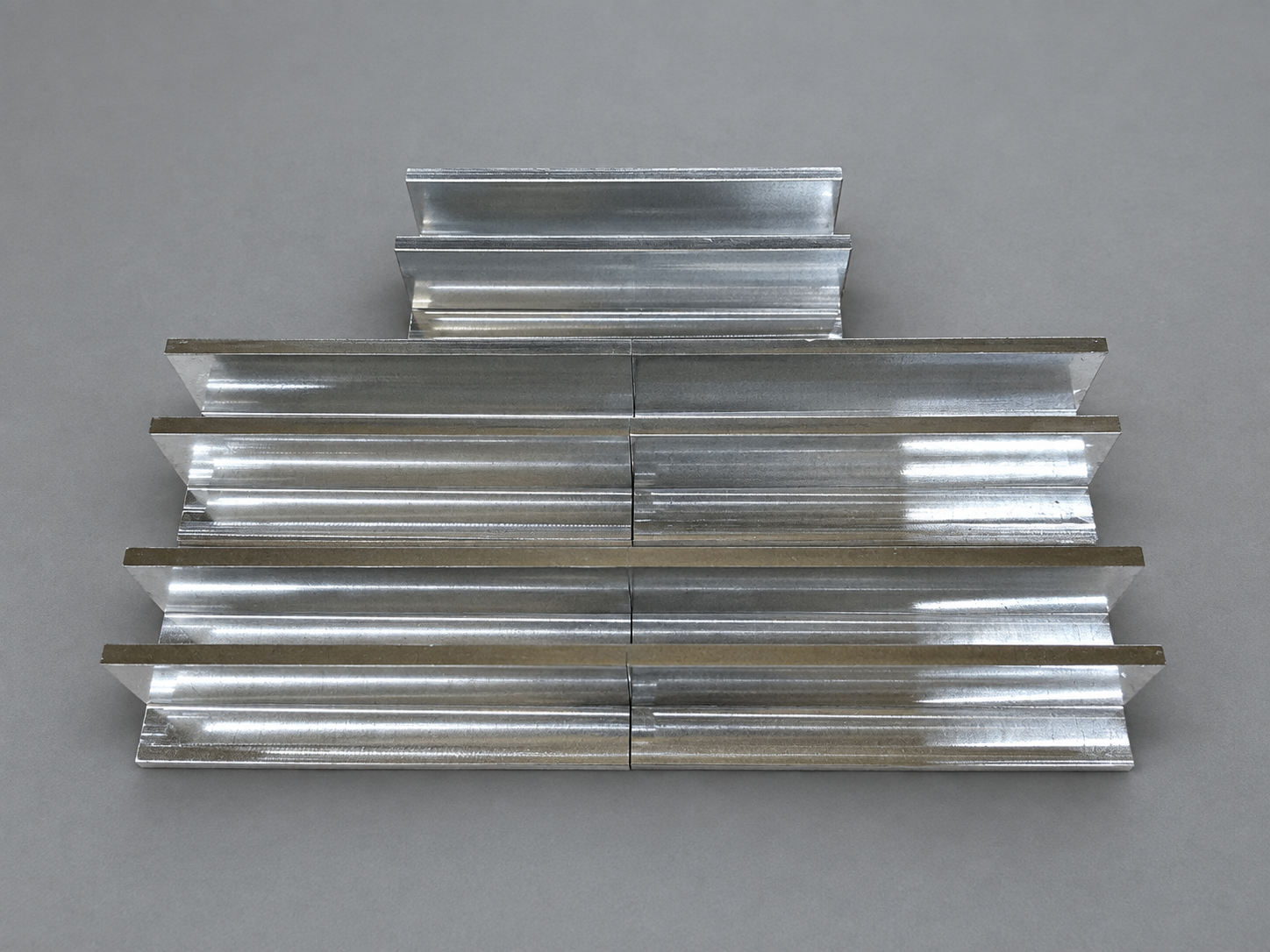 Batch of machined metal components with channel profiles arranged in rows