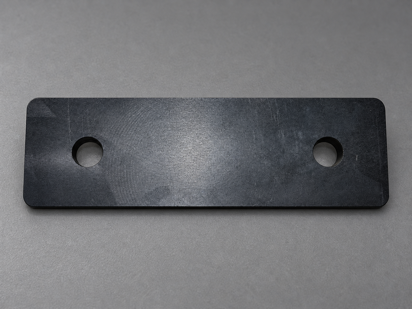 Black hardcoat anodized mounting plate with two mounting holes and rounded corners