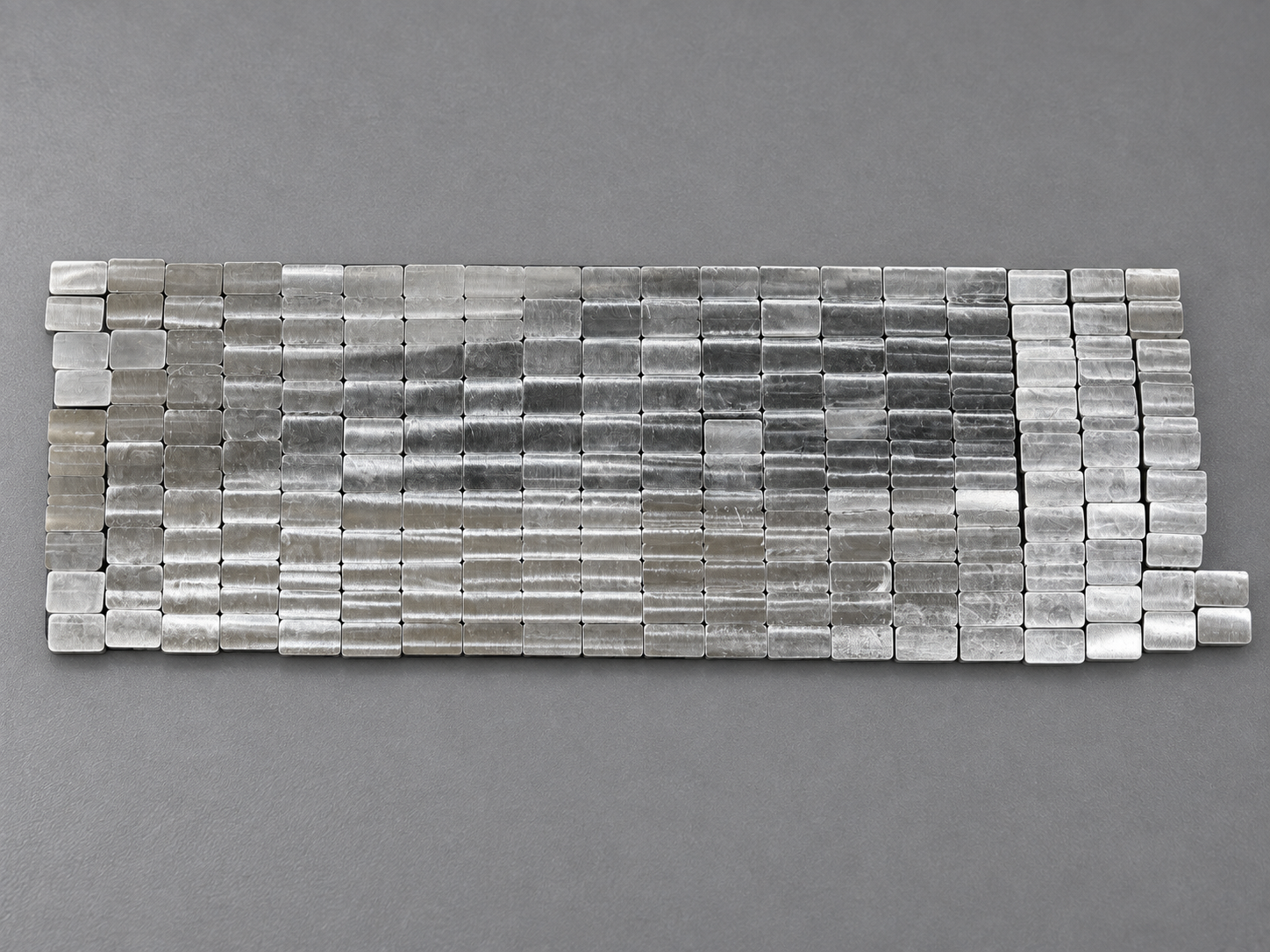 Production batch of small rectangular CNC machined components arranged in closely spaced rows